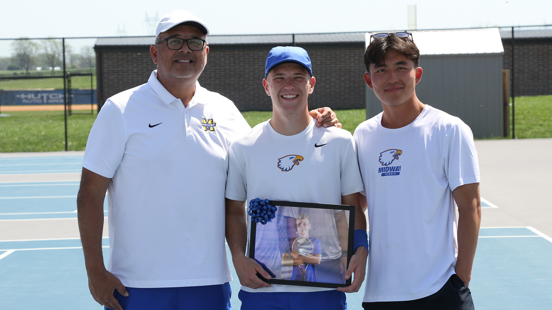 Owen McCarter (center) poses with head coach Adam Malik and assistant Ryan Lee during a senior day celebration held by the Midway men's tennis program Monday.